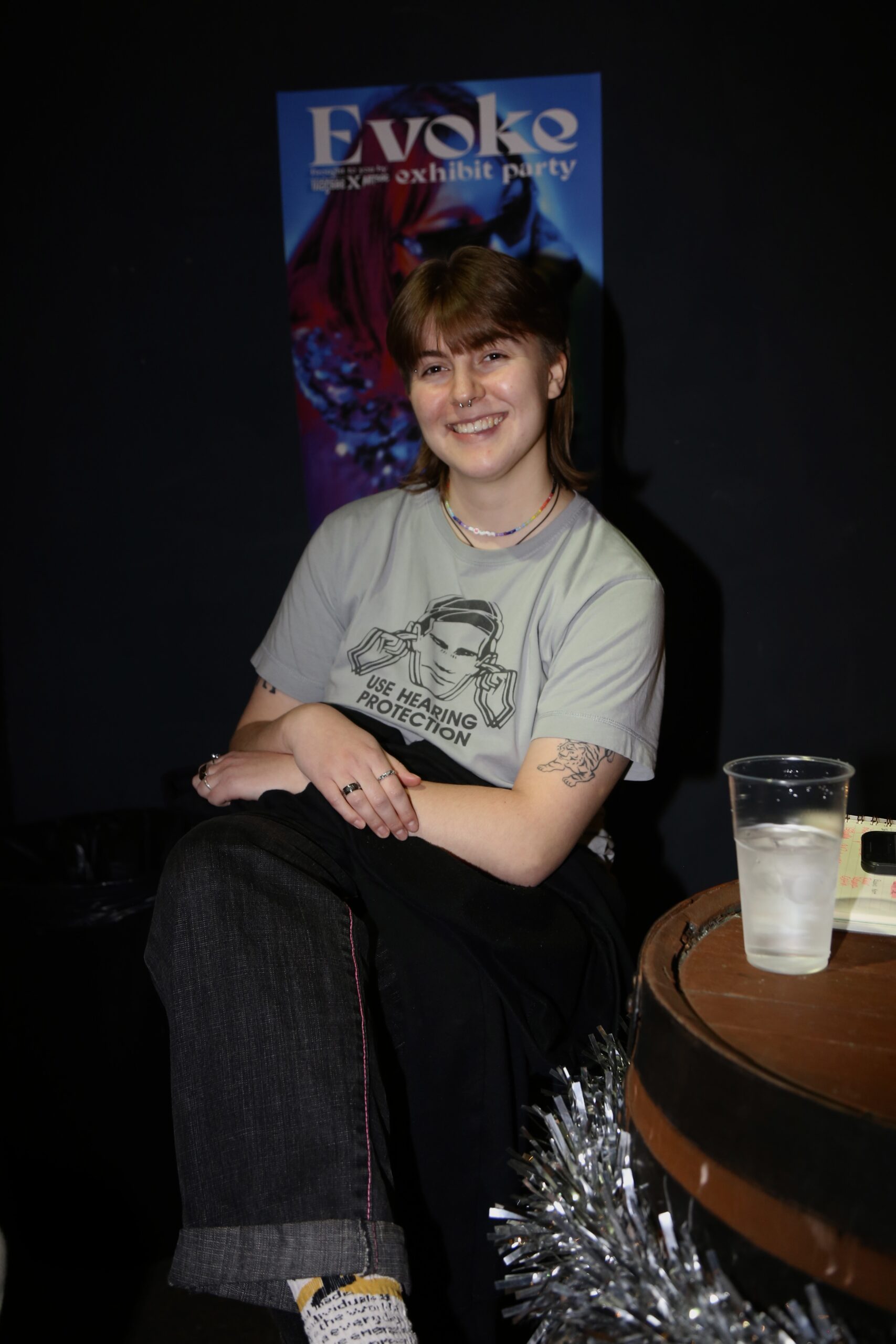 Magsoc's treasurer Amber Gaunt pictures sitting in front of an 'Evoke' poster.