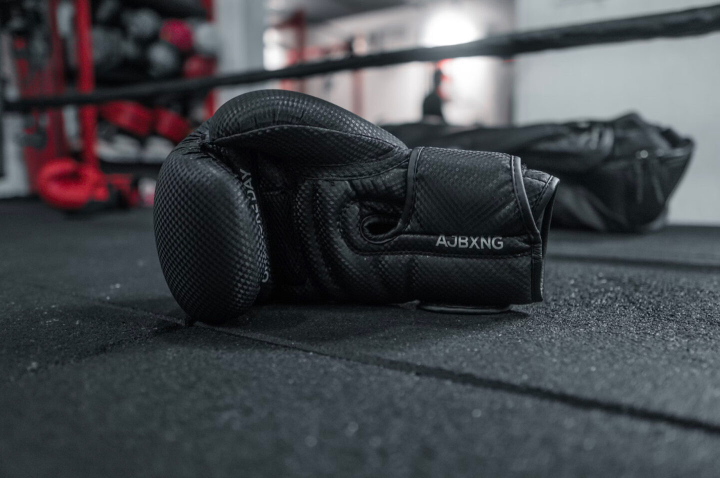 Image shows black boxing gloves laid out on a black boxing canvas